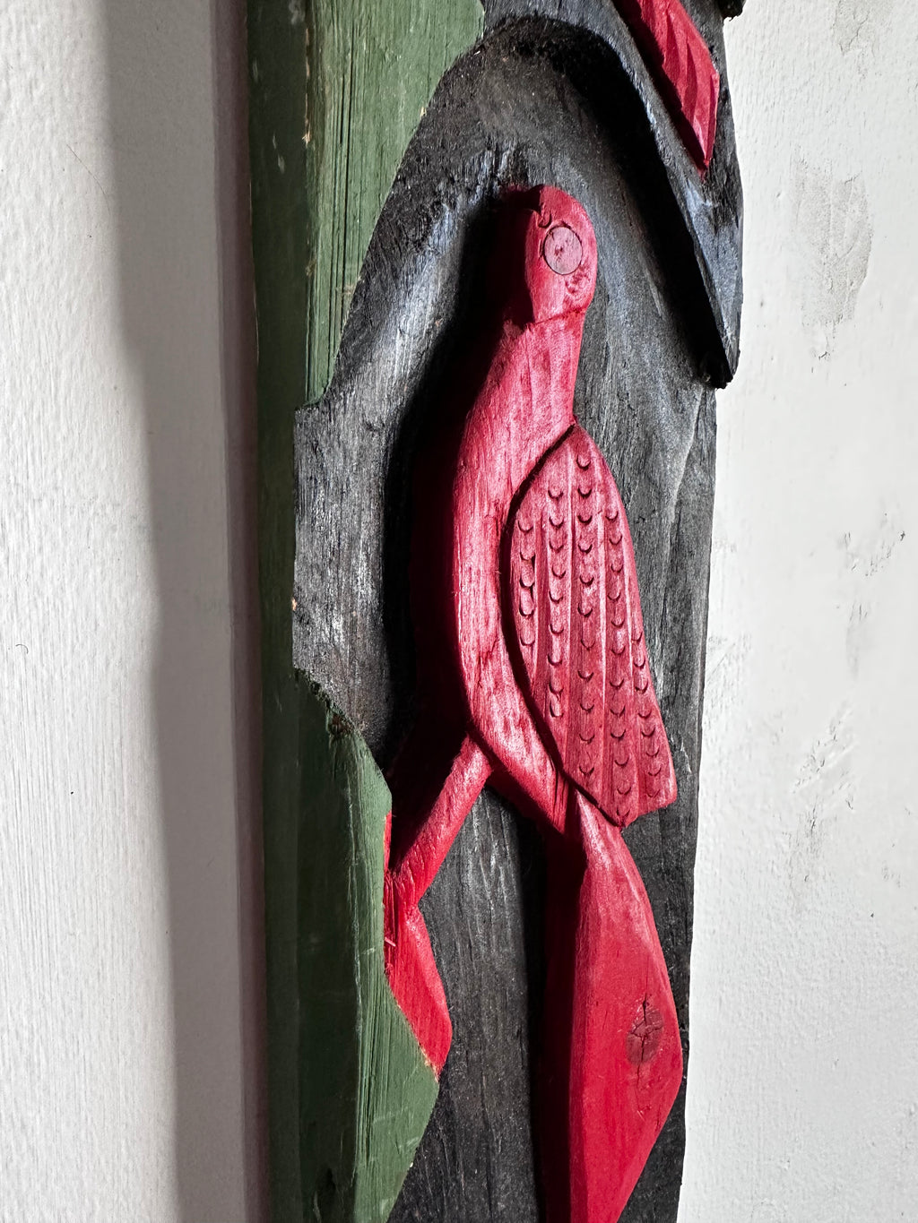 Carved wooden bird panel in red green and black