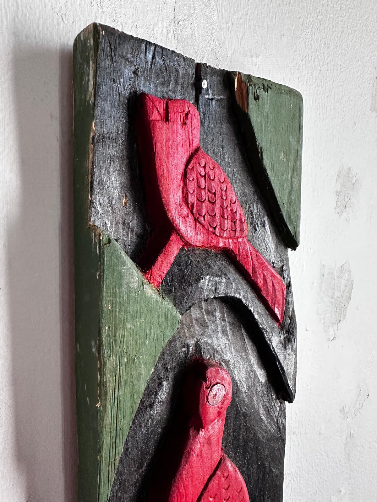 Carved wooden bird panel in red green and black