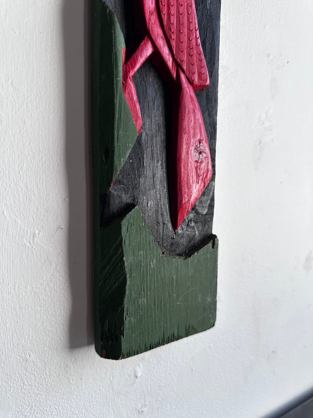 Carved wooden bird panel in red green and black