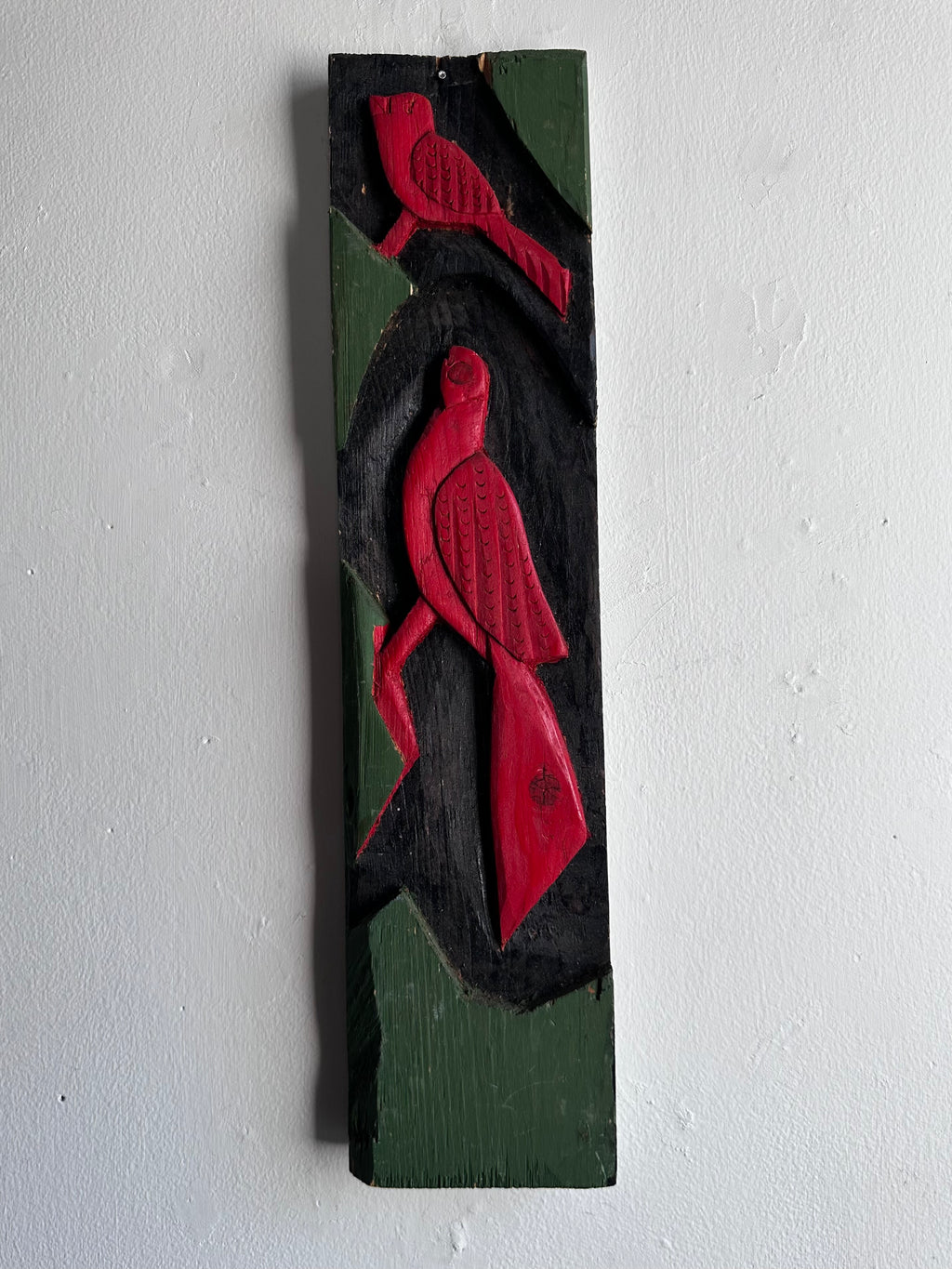 Carved wooden bird panel in red green and black