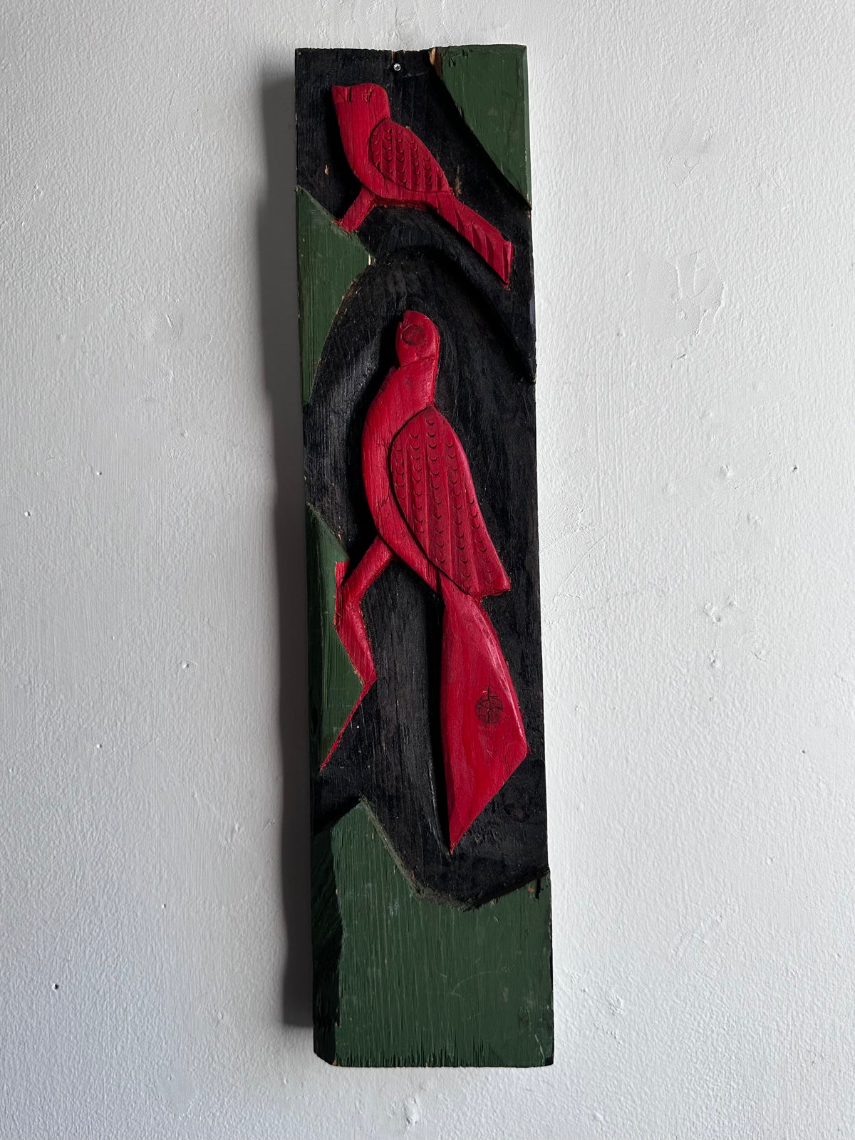 Carved wooden bird panel in red green and black
